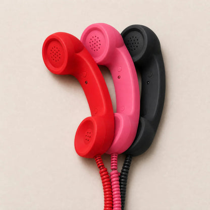 Tre cornette telefono retrò rossa, rosa e nera con cavo USB-C, la rossa collegata a uno smartphone